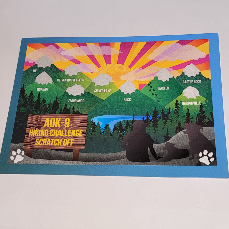 Colorful card with green snow-capped mountains representing the ADK-9 Hiking Challenge which is printed in yellow on a brown sign. A human silhouette and two canine silhouettes' are to the right. The mountains are named with white text inside them: JAY, MOXHAM, MT. VAN HOEVENBERG, FLOODWOOD, SILVER LAKE, BUCK, BAXTER, CASTLE ROCK, and BARONVILLE. 
