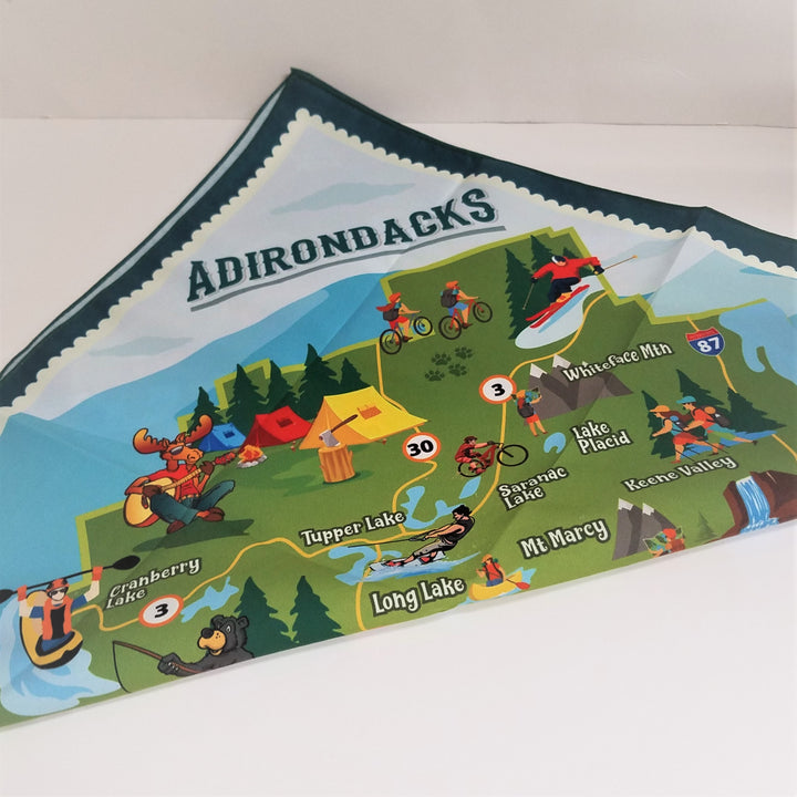 Adirondacks printed at the top triangle of this folded bandana with dark green border around a brightly colored map of icons and towns in the Adirondack mountains