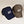 Two ADK panel caps. On the left a navy cap and to the right a brown cap. Both have white embroidery featuring  the letters ADK with the A in the style of a pine tree and a small hiker climbing the top of the K