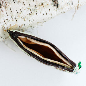 close up of zipper opening of bag next to birch log