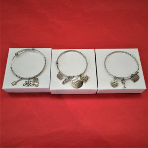 Three silver bangle bracelets set on white boxes on a red background.