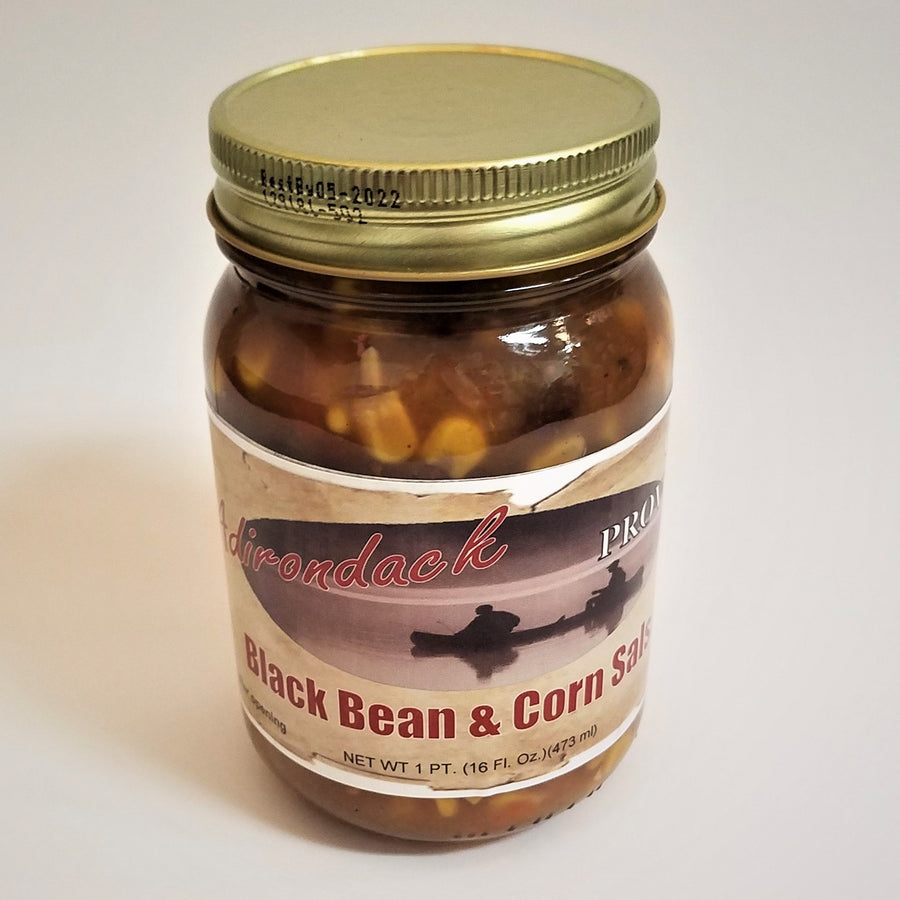 Glass jar of Black Bean & Corn Salsa. Yellow corn and a glimpse of black bean can be seen through the glass under the gold screw top.