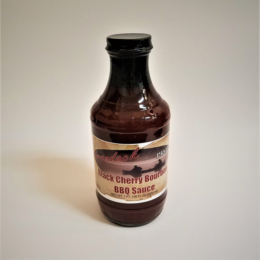 Glass bottle of Black Cherry Bourbon BBQ Sauce. The dark, rich sauce gives the glass bottle its color under the black screw top.