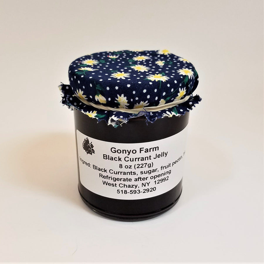 Yellow flowered with white dots on a navy cloth banded to a jar of Gonyo Farms Black Currant Jelly.