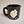 A single black-with-gray speckled camp mug with the words SARANAC LAKE, NY on the bottom and a white-filled outline of the Adirondack Park in the center. There is a small black heart in the white outline located where Saranac Lake sits. The mug has a black rim and black interior.