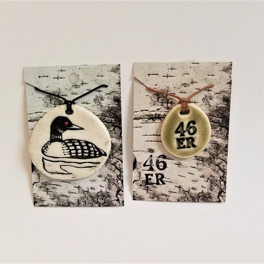 Both loon and 46er pendants pictured side by side on their package paper.