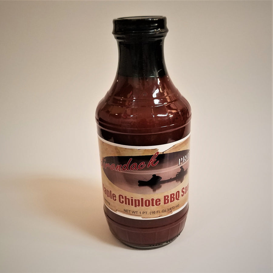 Glass bottle of  Maple Chipotle BBQ Sauce. The dark, rich sauce gives the glass bottle its color under the black screw top.