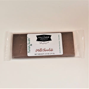 Milk chocolate bar in clear wrapping with the white label in center: The Village Mercantile. Barkeater Chocolates in green type on left side.