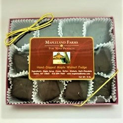 Box of dark chocolate candies with white crinkle paper surrounding each. Under a clear plastic top which has the Mapleland Farms label in the center and a gold elastic bow in left hand corner.