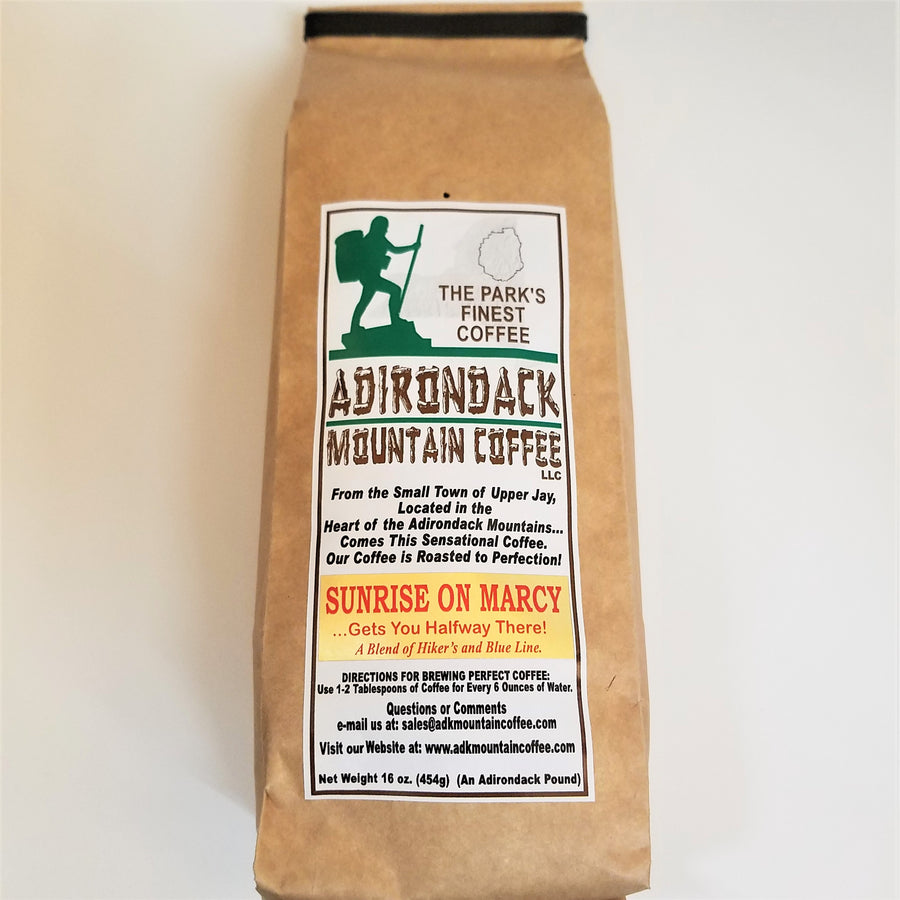 Brown-bag package of  Sunrise on Marcy of Adirondack Mountain Coffee. White label placed vertically in the center with green, brown and black type. Green illustration of a hiker and black outline of the Adirondack Park on top of label.