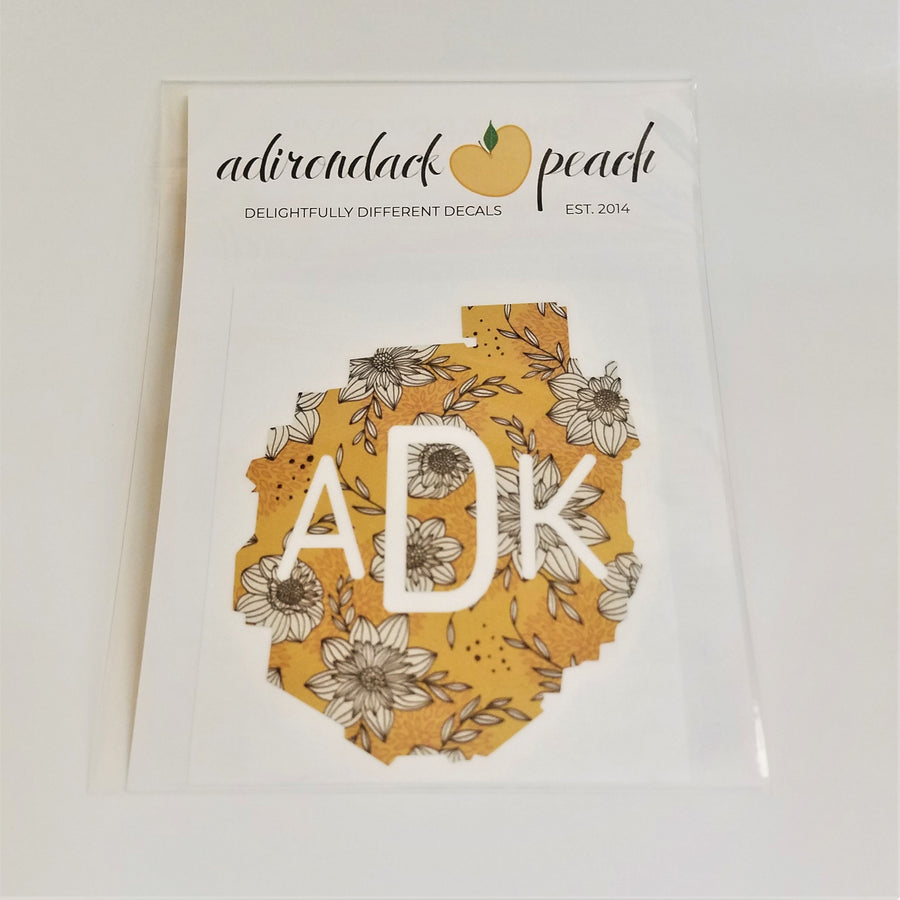 Decal of the Adirondack Park boundaries in yellow floral with white ADK lettering centered in the design.