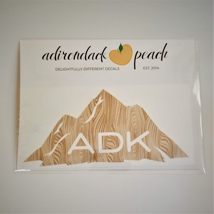 Adirondack mountain decal in wood grain pattern with white ADK lettering printed at the base of the mountain