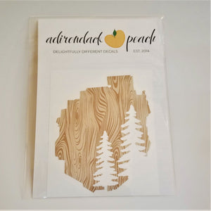 Decal of the Adirondack Park boundaries in wood grain pattern with two pine trees in white on the bottom right.