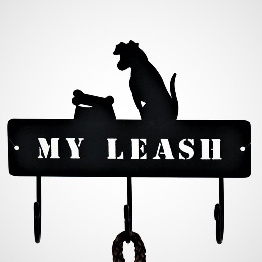 Close up of MY LEASH rack on a white background. 3 hooks below with part of a leash hanging on middle hook, words MY LEASH cut out of black metal above hooks and clear cut out of dog above this on the right and bowl and bone to the left of the dog.