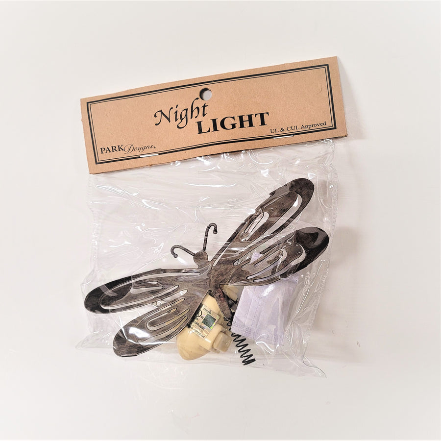 Metal dragonfly night light seen through its clear-plastic package. Top of package cardboard label features the words Park Designs Night Light