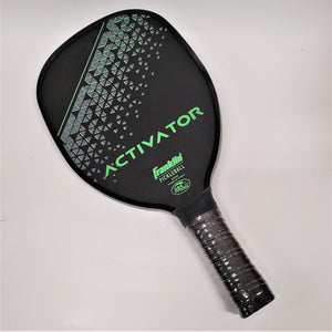 Pickleball paddle with black handle on the bottom. Top of paddle seen is black with green lettering: ACTIVATOR Franklin PICKLEBALL. More text below is hard to read. There is a gray diamond pattern on the top portion of the black on the paddle.