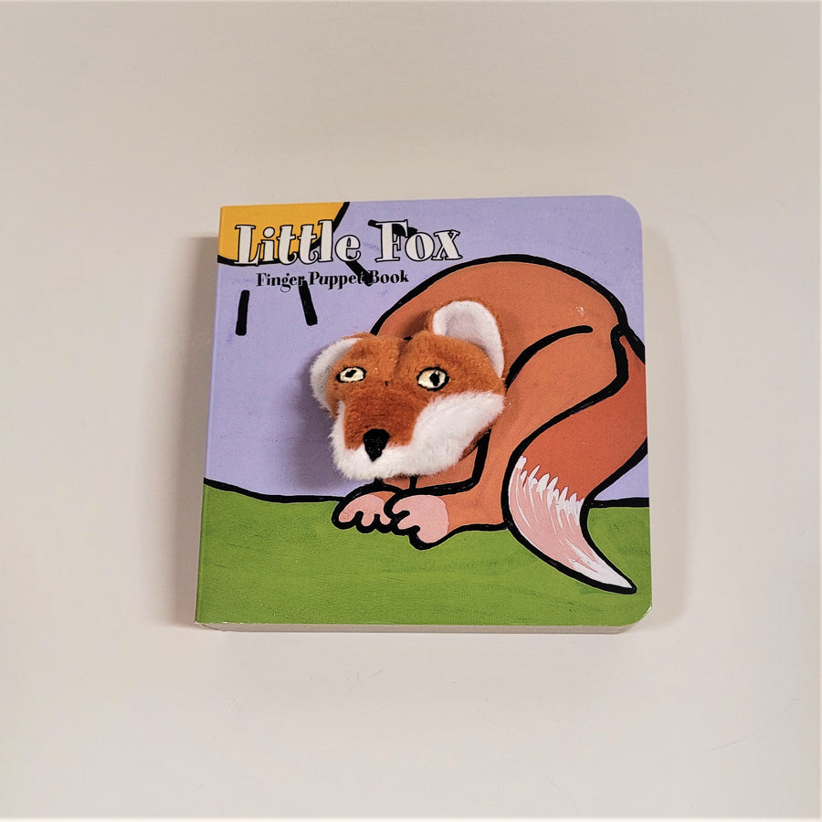 Little Fox finger puppet book with cloth head of fox coming out of the flat book cover. Fox is brown with black outlines and a white feathered tail set on solid green with a sky and partial sun behind.