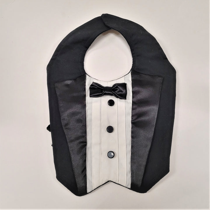 Black and white tux-like bib for an infant or for dressing up the canine, seen here lying flat and clasped at the back (neck).