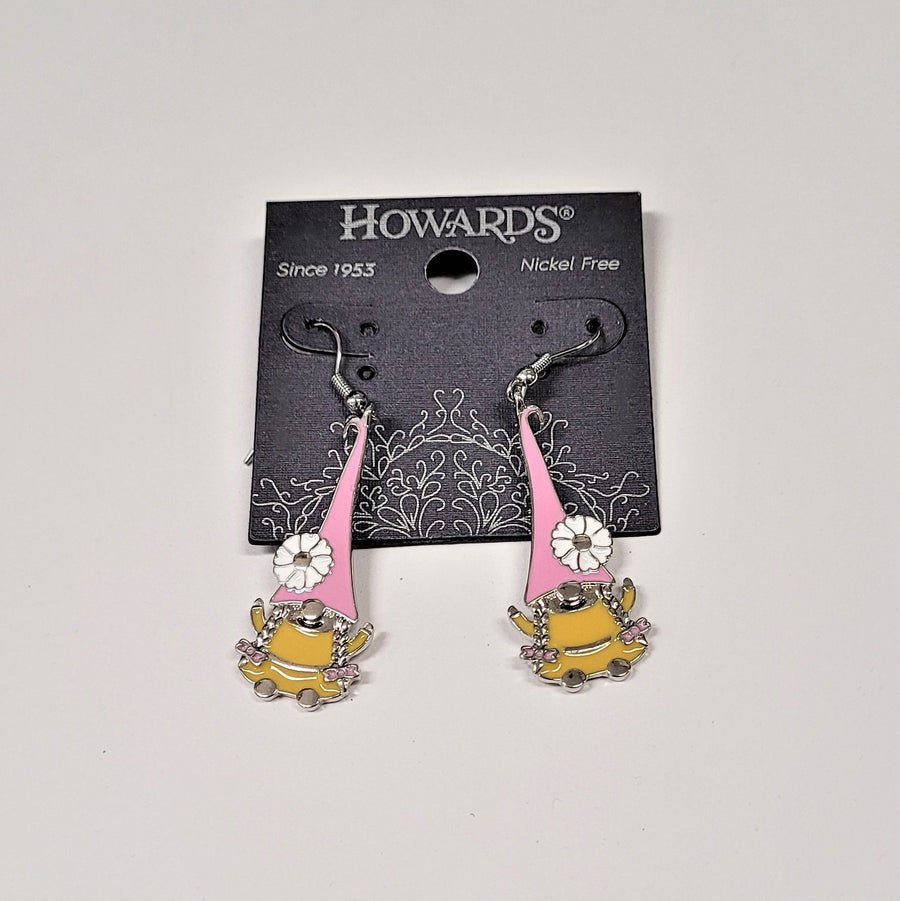 Playful-looking gnomes hang from silver hoops on black Howard's packaging. The gnomes each have long pink pointy hats with a white flower near the bottom on the outside edge. The body of the gnome is gold with a silver nose and two braids hanging from the hat on each side of the nose.