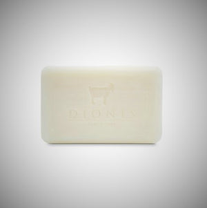 Unscented DIonis Goat Milk Soap out of box standing flat. Image of a goat and DIONIS type can be scene faintly etched into the soap.