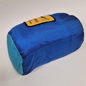 Hammock packed in its Columbia blue and aqua blue sack leaning on its side with gold label partially showing in the back.