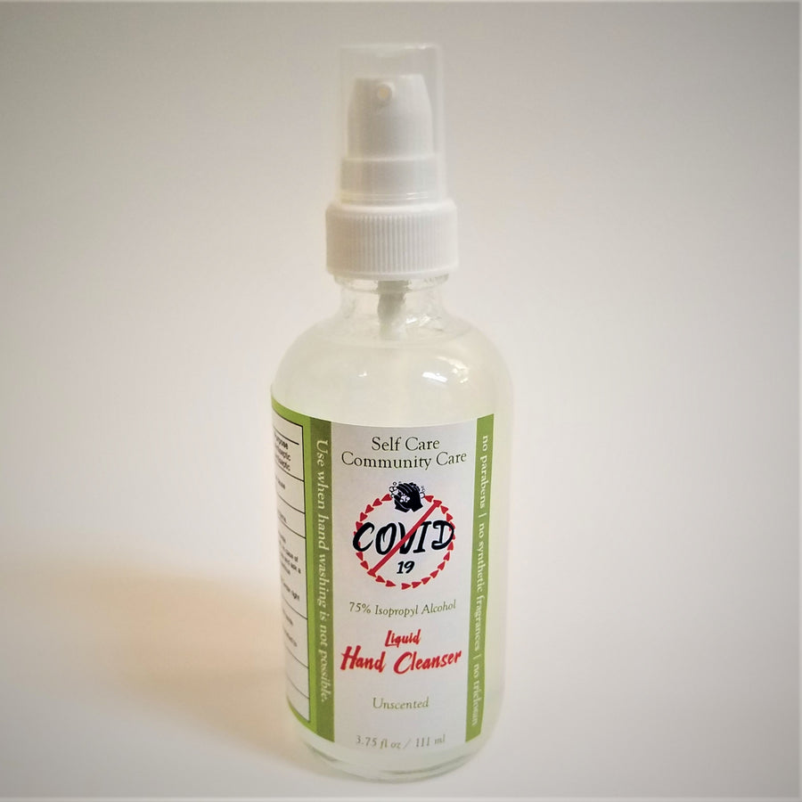 CLear glass bottle with white plastic spray top. White and green label on hand sanitizer bottle with no-COVID 19 symbol in center