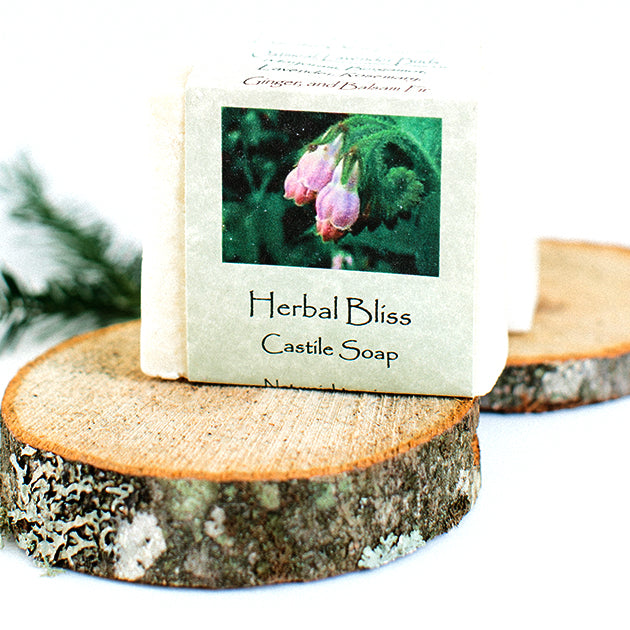Packaged Herbal Bliss Castile Soap standing face out on two wooden discs.