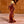 Glass maple syrup bottle filled with syrup and shaped like a hockey player with a gold-colored screw top sits on a wooden-slatted table.