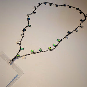 Lanyard chain featuring fishing lures with lots of green and blue glass spread out flat attached by hook to a plastic ID holder.