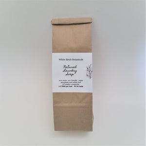 Single brown paper bag on a white backdrop. A while label in the center has black type saying White Birch Botanicals with the lettering Natural Laundry Soap in the center and more washing details printed below.