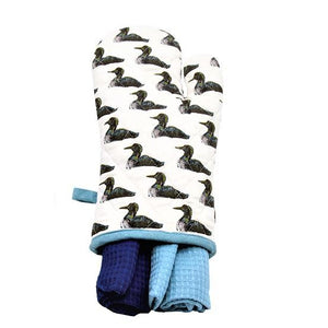 White oven mitt with black and white loons printed all over. A light blue hanging loop is on the left and two blue (one navy, one light) dishtowels are in the mitt opening on the bottom.