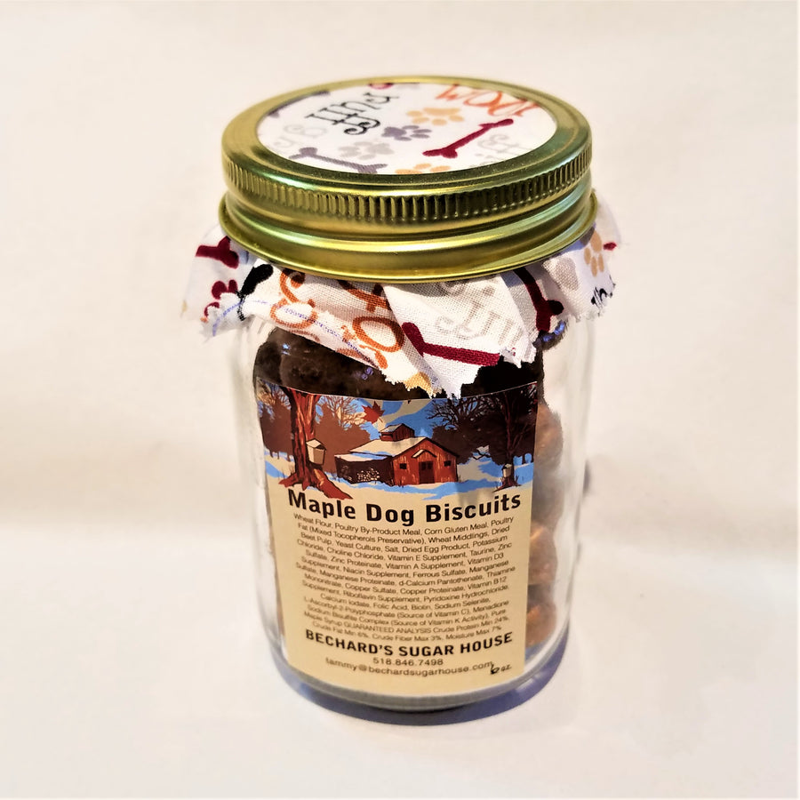 Mason jar packing with Maple Dog Biscuit beige label, fabric-lined top of jar with white fabric colored with brown and gray bones, yellow and gray paw prints, and decorative lettering like ruff.