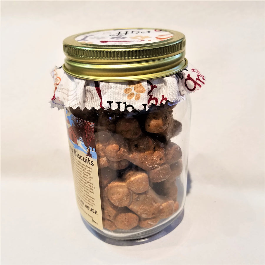 Side, standing view of  the clear part of the mason jar showing the maple dog biscuits inside with the fabric-lined top of jar also visible.