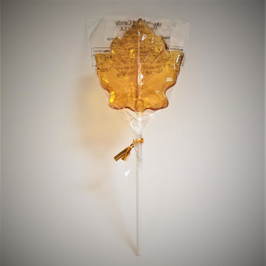 Maple leaf-shaped maple lollipop standing with white stick pointing down and leaf candy at the top.