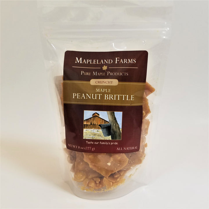 Mapleland Farms Maple Peanut Brittle package standing with label top-centered and peanut brittle pieces seen through the clear plastic bag.
