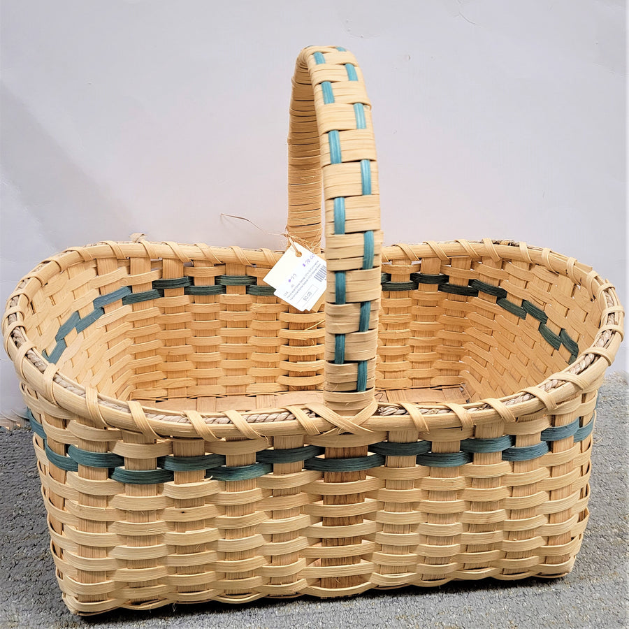 Market basket in neutral weave with green trim showing in the top third of the front and in the inside of the basket as well as in the front on the handle above the basket.