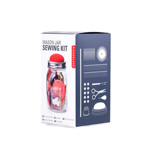 Boxed package of Mason Jar Sewing Kit. Box has white front with color photo of the clear jar with red cushioned top. Side of box is gray with white illustrations of all the tools inside: scissors, needles, thimble, needlethreader, etc.