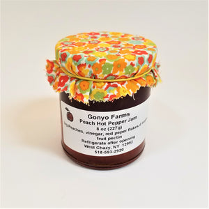 Colorful yellows and orange flowered cloth banded to a jar of Gonyo Farms Peach Hot Pepper Jam.