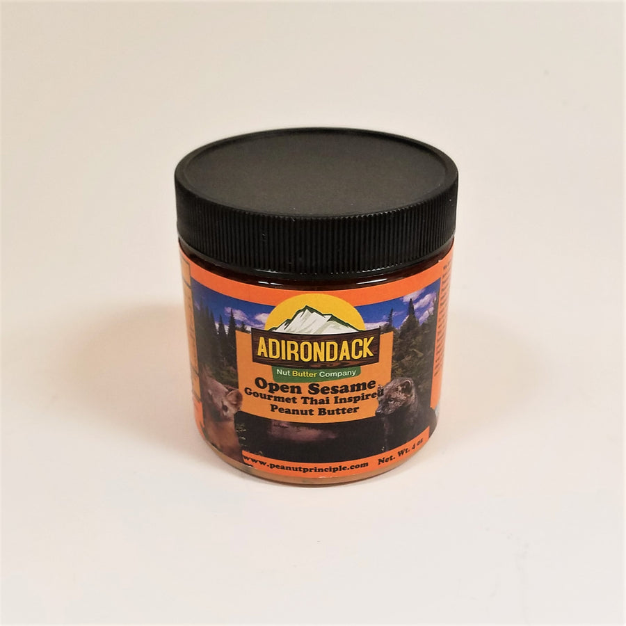 Open Seasme gourmet peanut butter in its plastic jar with a black screw lid. Ferrets and forest are featured on the label surrounding the type.