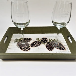 Pine cone tray flat view with two Saranac Lake engraved wine glasses atop.