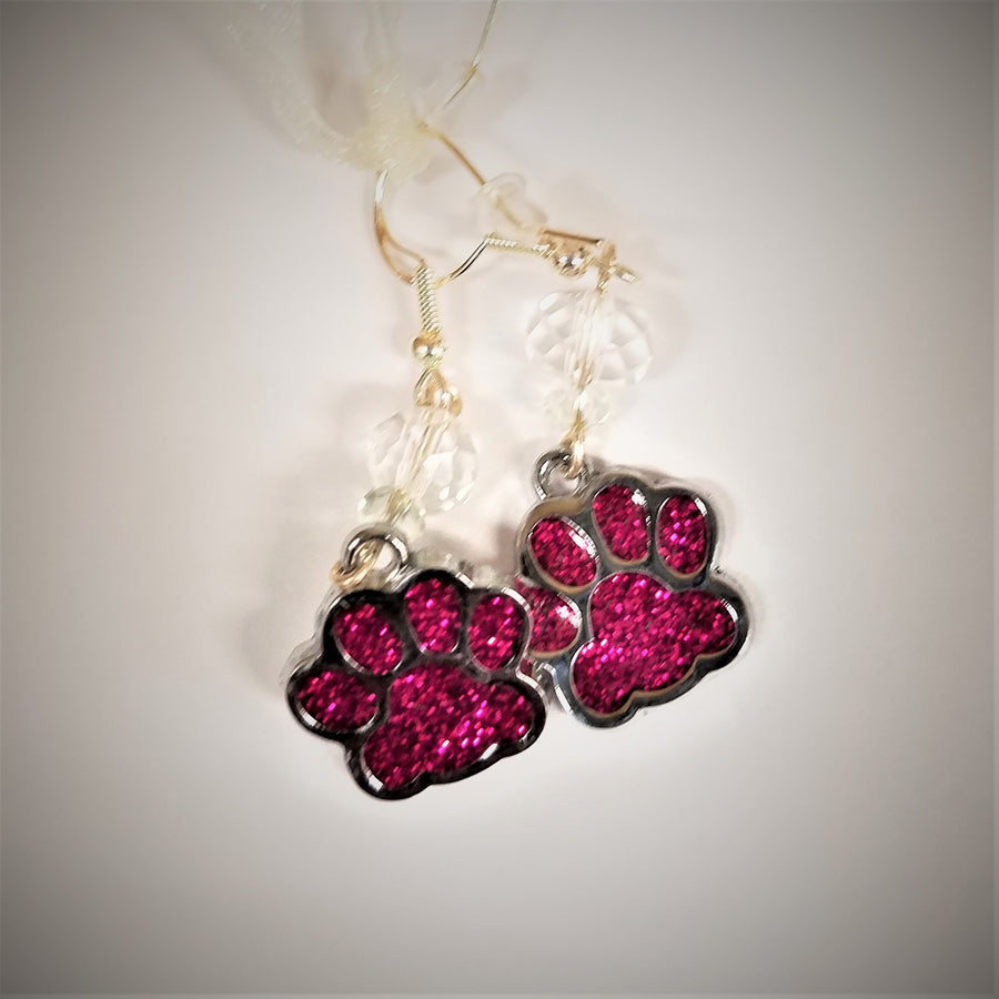 Pink glass dog paw earrings lying flat with clear glass beads above them.
