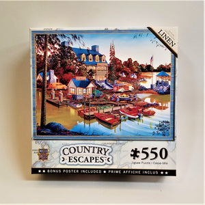 Box cover for 550 piece puzzle. Pictured are boats docked in water in front of an old-time resort with a gazebo to the right of the inn.