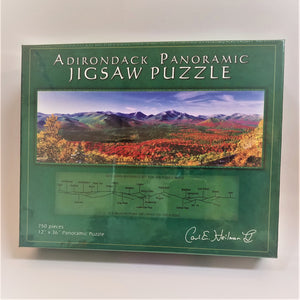 Cover of Adirondack Panoramic Jigsaw Puzzle Box features a green border surrounding an autumn-colored mountain and valley scene. Below the photo is a reference chart of the mountains depicted.