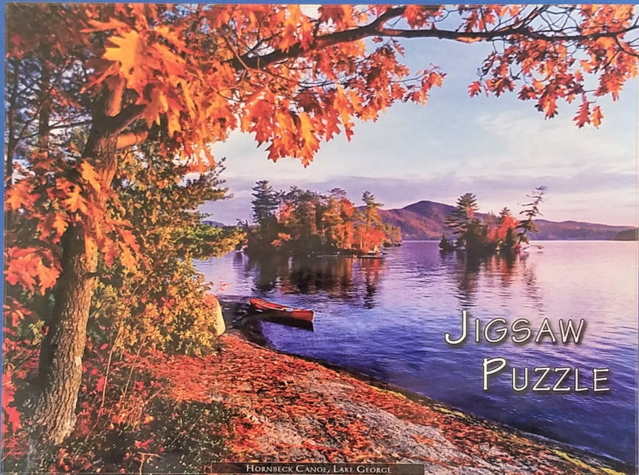 Just the photo from the box cover of the Hornbeck Canoe, Lake George. Purple water and fall-foliage on the land with a red canoe in the water close to the left bank.