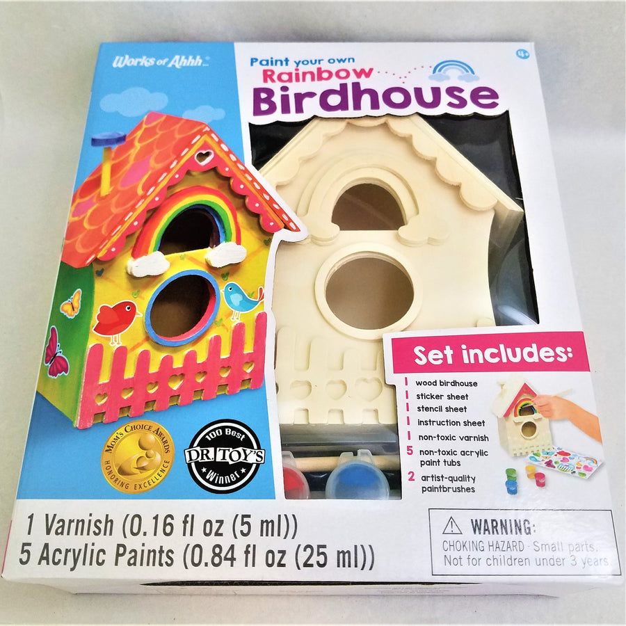 Box of a Paint Your Own Rainbow Birdhouse shows the unpainted house through the clear plastic part of the box, along with two small containers of blue and red paint. There is an image of a completed house and a list of what the set includes.