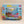 Puzzle box cover for 101 things to spot underwater. Blue border with various sea images. A thin white border surrounds a brown shipwreck and lots of colorful underwater life, treasure and more.