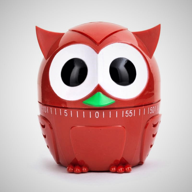Red owl kitchen timer facing front out of packaging. Two big black eyes surround by white circles over a fan-shaped green beak above the split for the timer numbers and lines. The bottom is solid red with appropriate owl-molded paws and feathers on the sides.