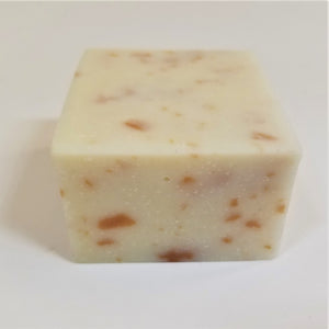Off-white square soap bar with orange speckles on top and front side.
