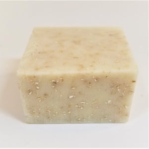 Off-white square soap bar with beige speckles on front side and top of bar.