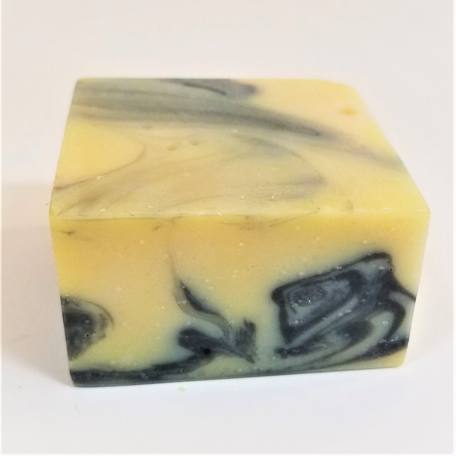 Yellow soap square bar with dark blue marble on front side and top of bar.